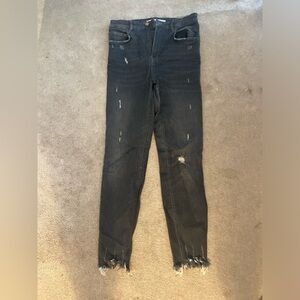 Distressed dark grey skinny jeans with a frayed hem.